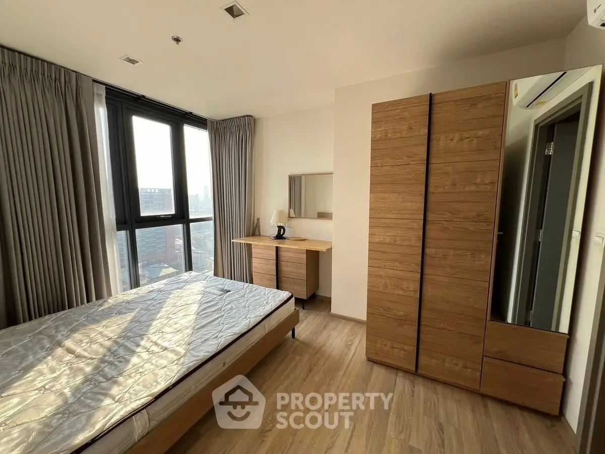 Spacious bedroom with large windows and wooden furniture, offering a cozy and modern living space.