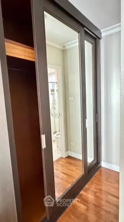 Spacious bedroom with mirrored sliding wardrobe and wooden flooring