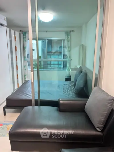 Modern bedroom with glass partition and stylish seating area in a contemporary apartment.