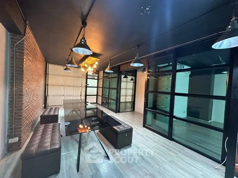 Modern industrial-style living room with exposed brick and sleek glass partitions.