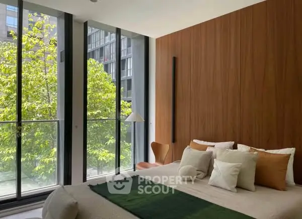 Modern bedroom with floor-to-ceiling windows and lush greenery view.