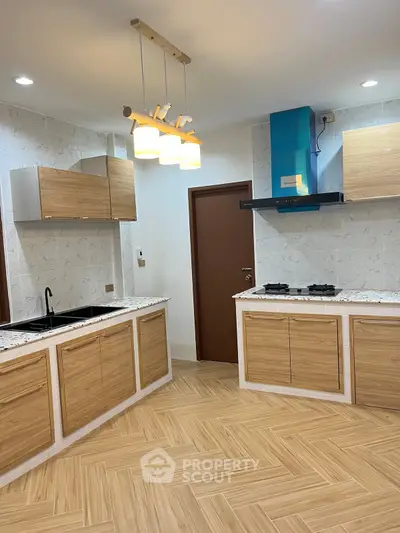 Modern kitchen with wooden cabinets, gas stove, and stylish lighting in a contemporary home.