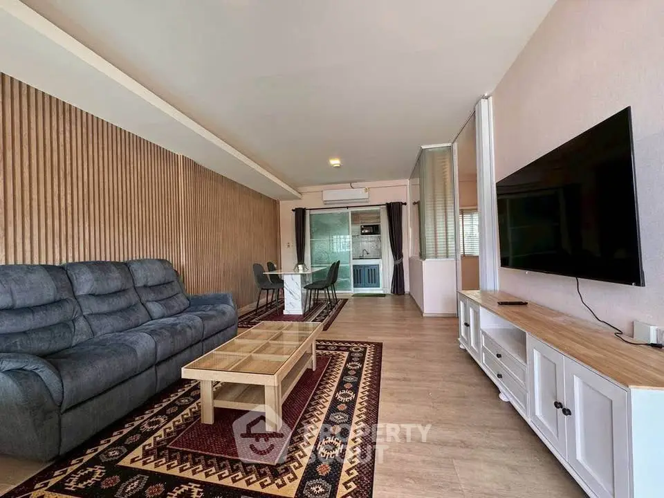 Spacious living room with modern furniture and large TV, perfect for relaxation.