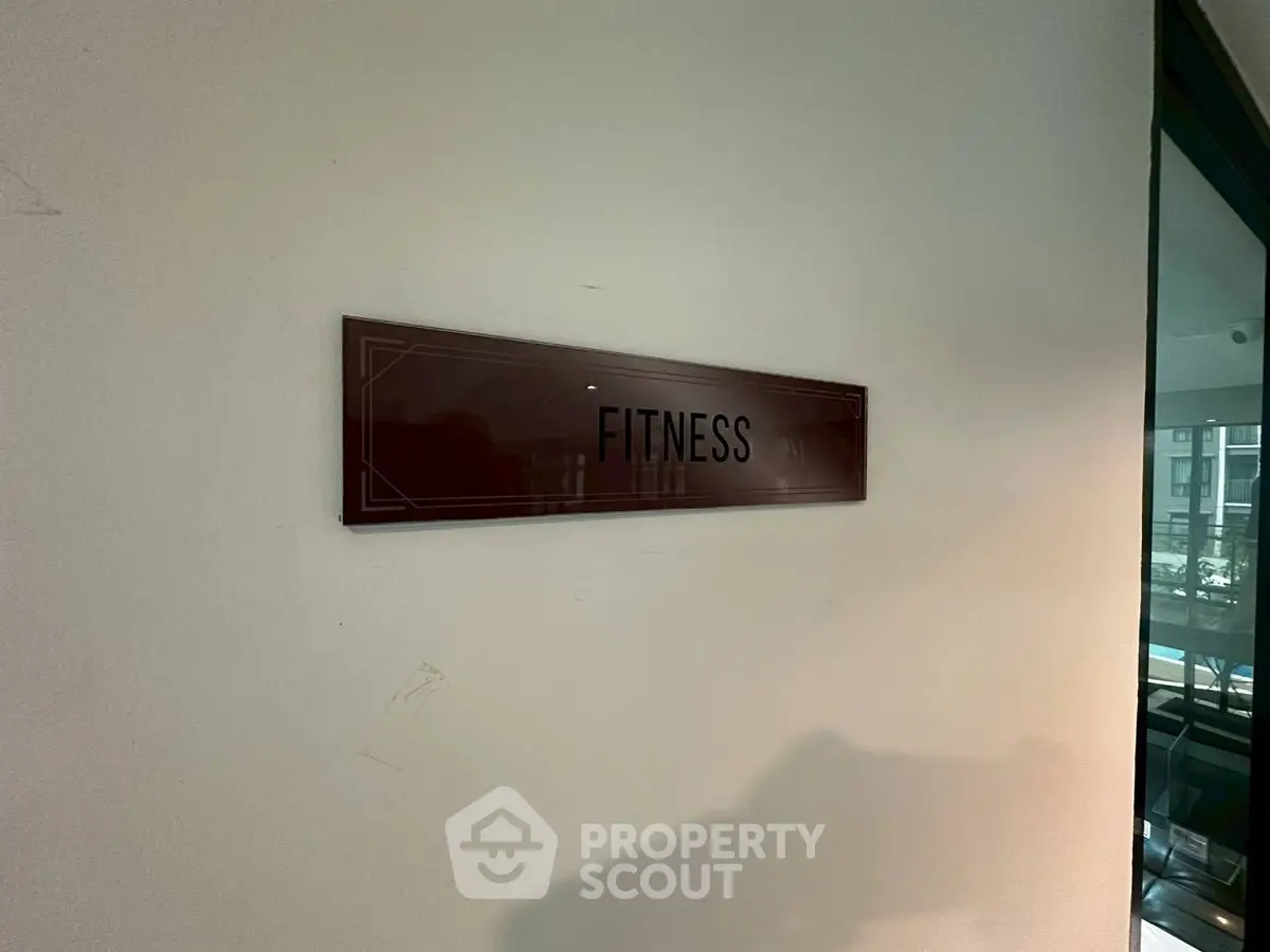 Modern fitness center entrance with sleek signage in upscale residential building.