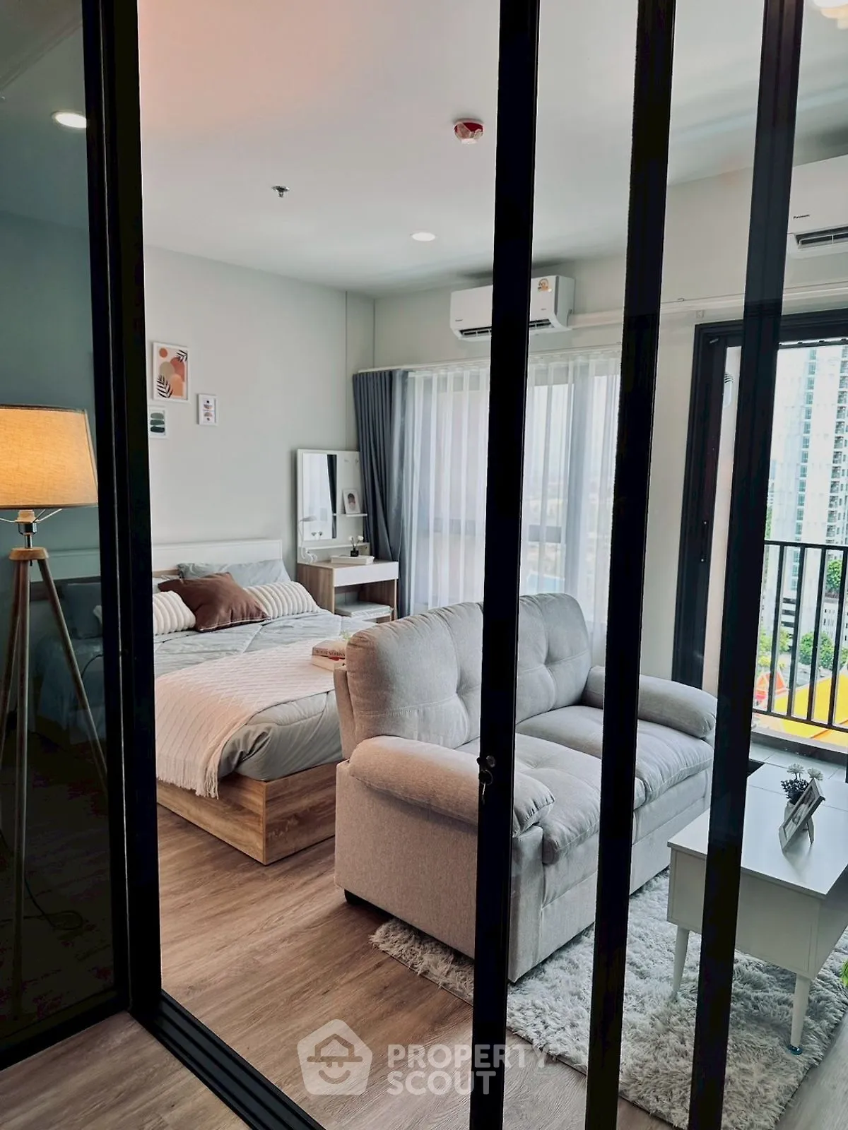 Modern studio apartment with cozy living area and bedroom, featuring a large window and stylish decor.