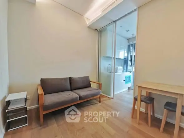 Modern living room with wooden flooring and compact furniture, featuring a cozy sofa and dining area.