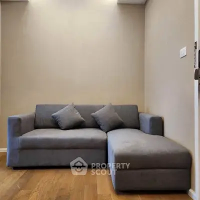 Modern living room with sleek gray sectional sofa and wooden flooring.