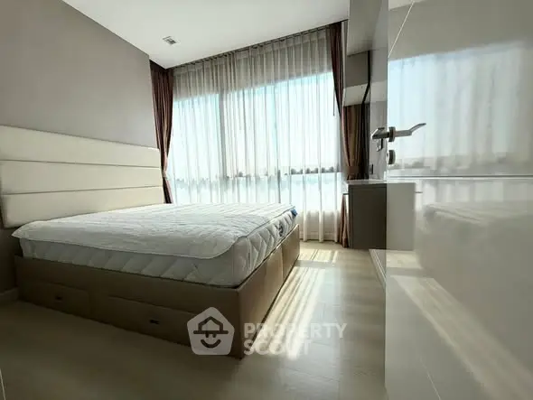 Modern bedroom with large window and elegant curtains, featuring a comfortable bed and sleek design.