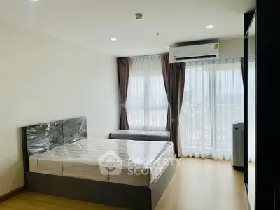 Spacious bedroom with large windows and modern furnishings in a high-rise apartment.