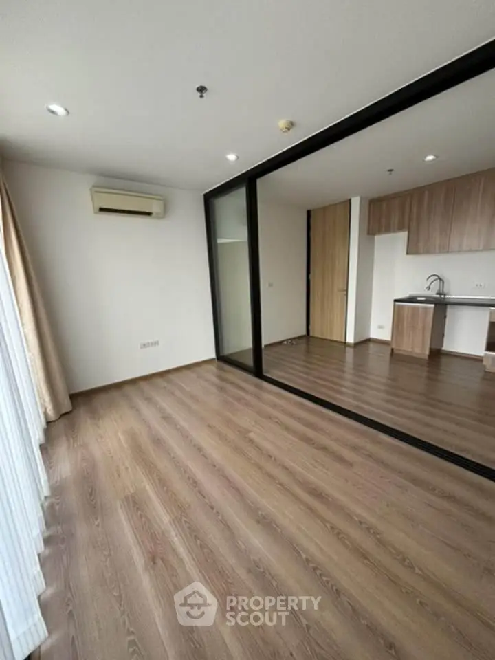 Spacious modern living room with wooden flooring and open kitchen layout in a stylish apartment.