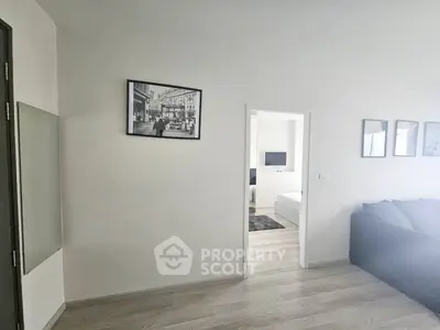 Modern apartment interior with open living room and bedroom view, featuring stylish decor and wooden flooring.
