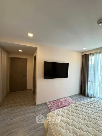 Modern bedroom with wall-mounted TV and large window for natural light