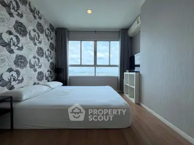 Spacious bedroom with floral accent wall and large window offering city views.