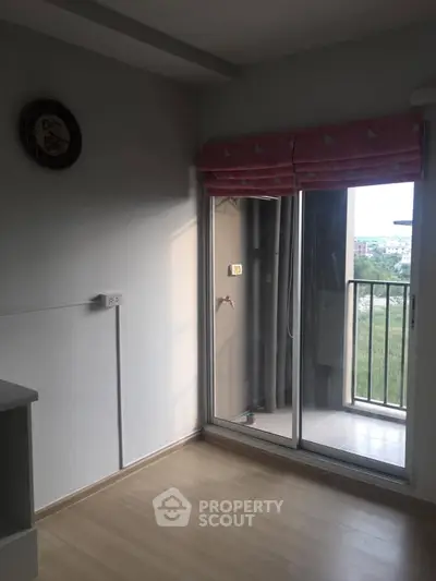 Bright room with sliding glass door leading to a small balcony, offering a serene view.