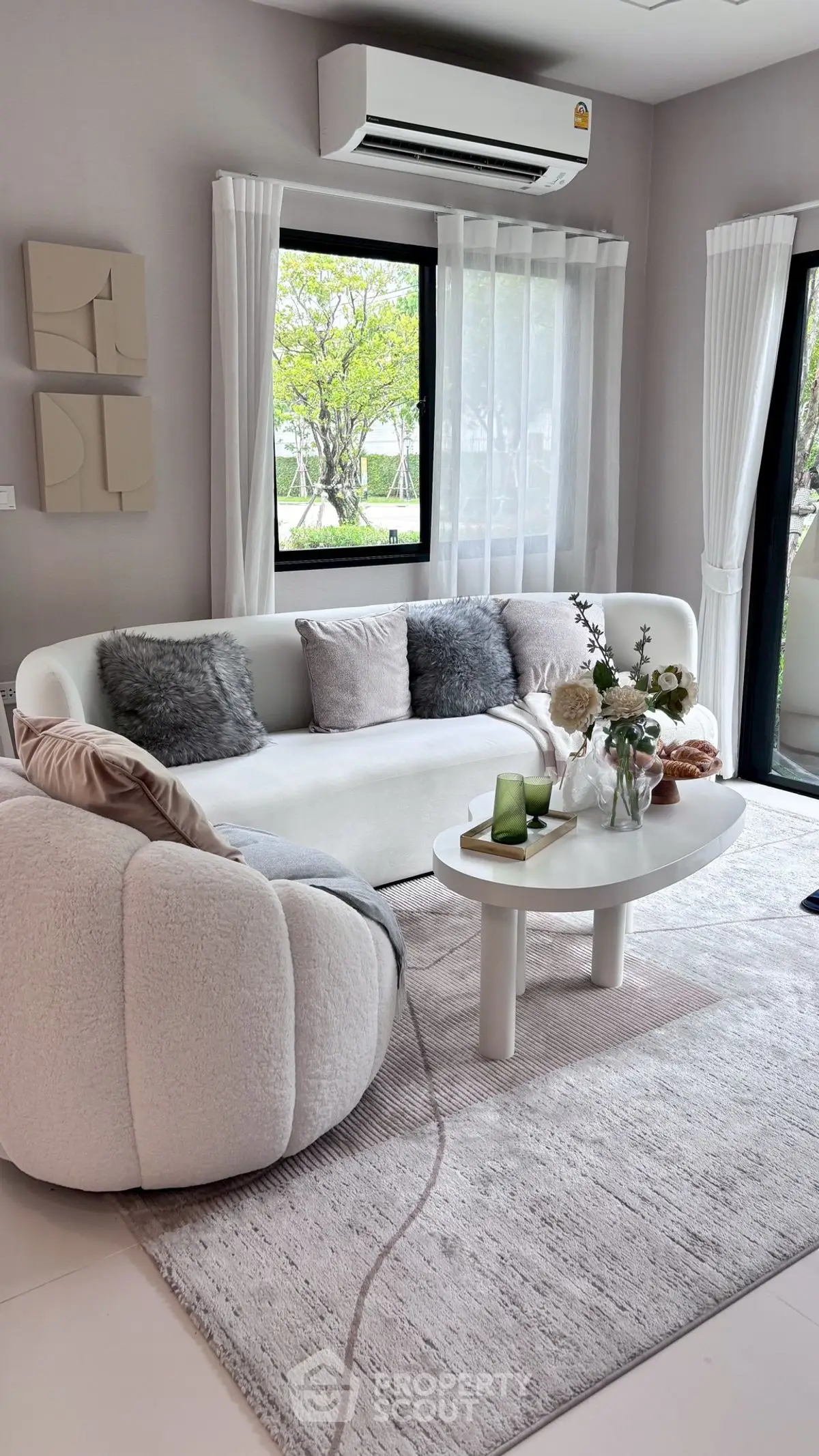 Modern living room with cozy seating and large windows offering a garden view.