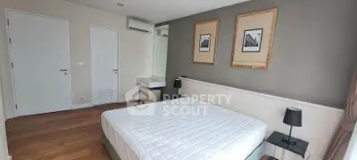 Modern bedroom with minimalist decor and wooden flooring in a stylish apartment.