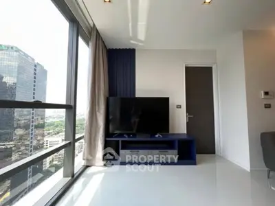 Modern living room with large windows and city view, featuring sleek TV setup.