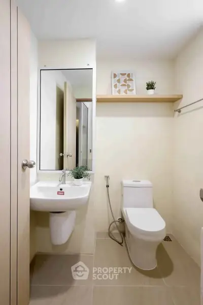Modern bathroom with sleek fixtures and minimalist decor, featuring a wall-mounted sink and contemporary toilet.