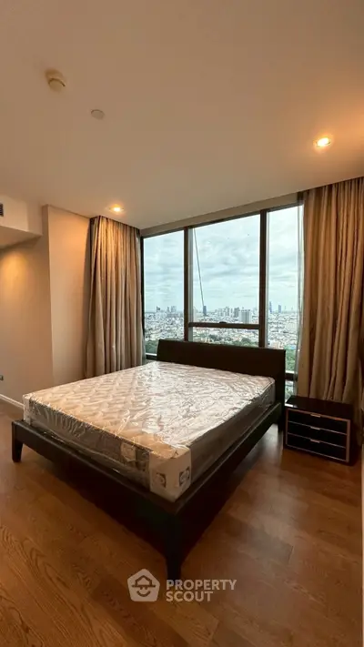 Spacious bedroom with large windows offering stunning city views and natural light.
