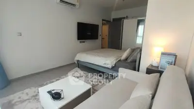 Modern bedroom with cozy seating area and wall-mounted TV in stylish apartment.