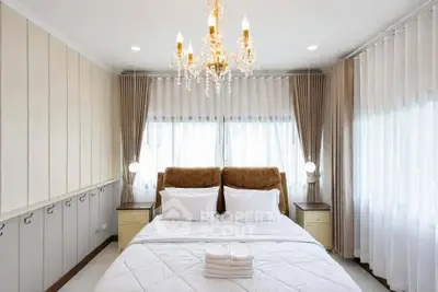 Luxurious bedroom with elegant chandelier and plush bedding in a bright, airy space.