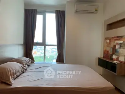 Cozy bedroom with large window and modern art, offering city views and natural light.