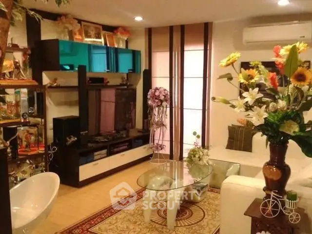 Stylish living room with modern decor, glass coffee table, and vibrant floral arrangements.