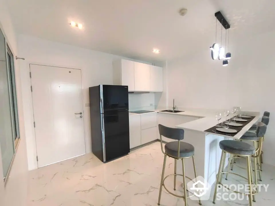 Modern kitchen with sleek black fridge and stylish breakfast bar seating