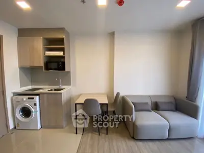 Modern living room with compact kitchen and cozy sofa in open layout apartment.