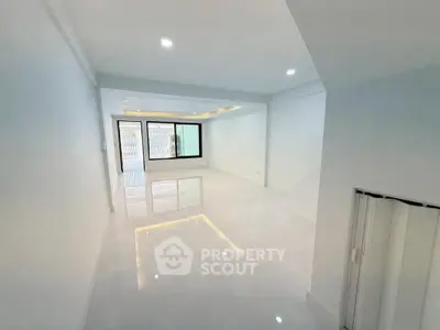 Spacious modern living room with sleek white flooring and large windows for natural light.
