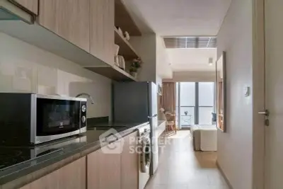Modern kitchen with sleek appliances and open layout leading to a bright living area with a view.
