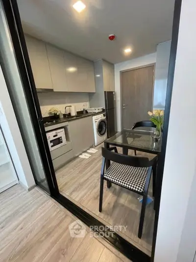 Modern kitchen with sleek cabinets, dining area, and built-in appliances in stylish apartment.