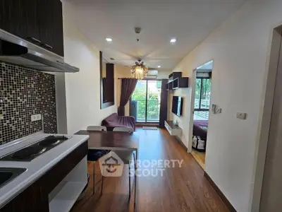 Modern open-layout living room with kitchen and balcony view, featuring stylish decor and natural light.