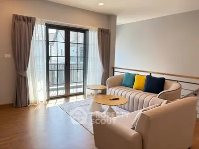 Bright living room with modern furniture and balcony access, featuring elegant curtains and wooden flooring.