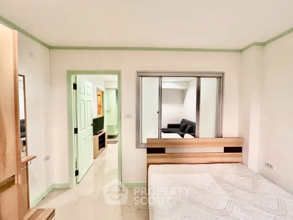 Spacious bedroom with modern decor and adjacent living area in a stylish apartment.