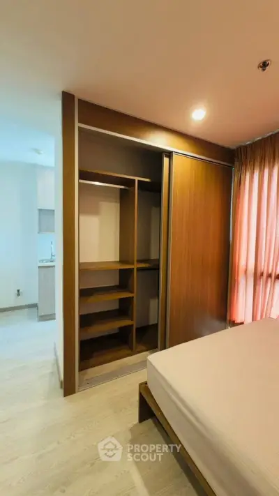 Modern bedroom with built-in wooden wardrobe and natural light from large window.