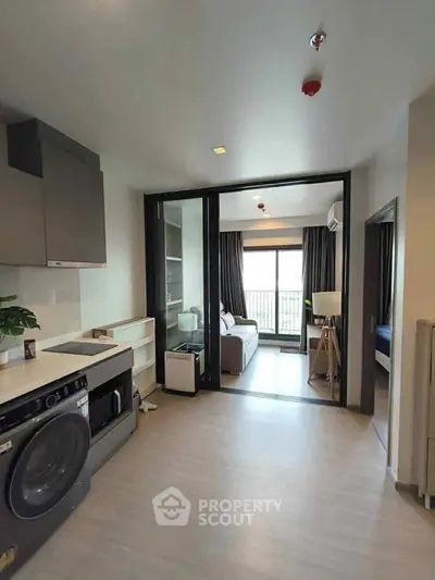 Modern apartment with open layout and washing machine, featuring a cozy living area and balcony view.