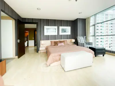 Spacious modern bedroom with large windows and stylish decor in a high-rise apartment.