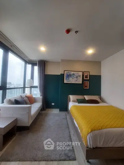 Modern bedroom with city view, stylish decor, and cozy seating area.