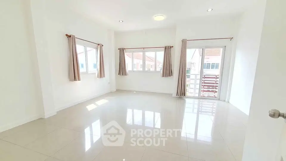 Spacious sunlit room with large windows and balcony access, perfect for modern living.