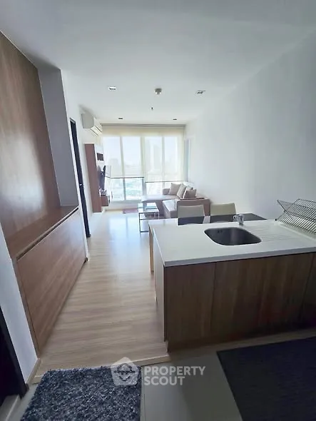 Modern open-layout living room with kitchen, featuring sleek design and large windows for natural light.