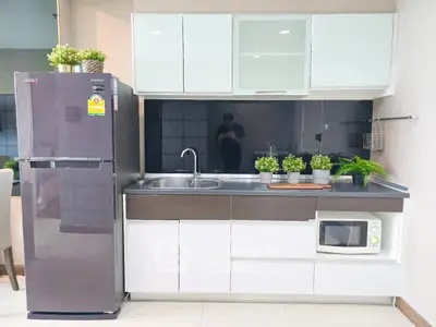 Modern kitchen with sleek cabinets, stainless steel fridge, and built-in microwave.