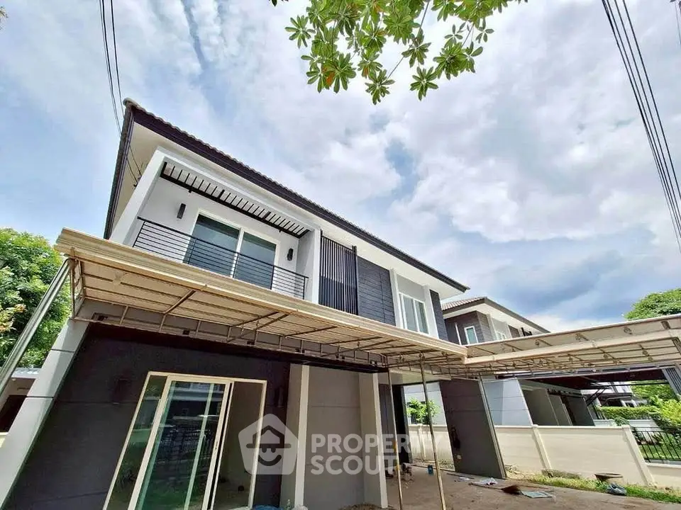 Modern two-story house with sleek design and spacious balcony under a clear sky.