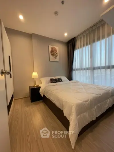 Modern bedroom with cozy lighting and large window in stylish apartment.