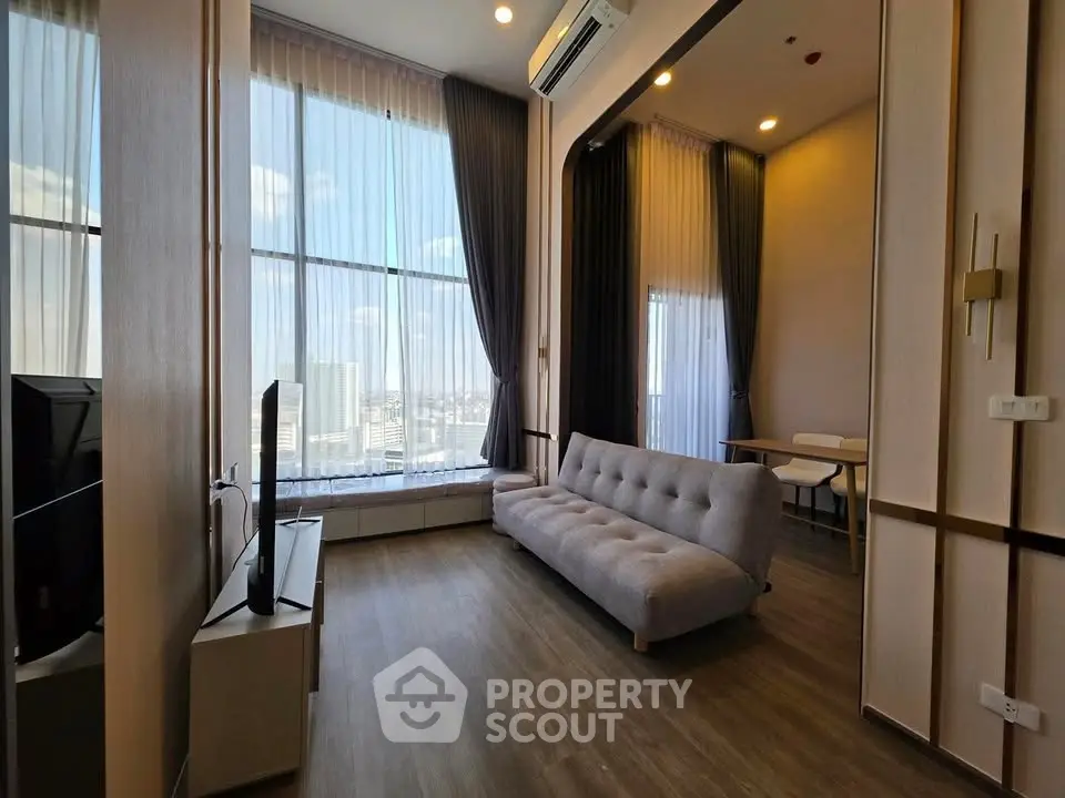 Modern living room with large windows and stylish decor in a high-rise apartment.