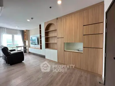 Spacious modern living room with built-in wooden cabinetry and large windows offering natural light.