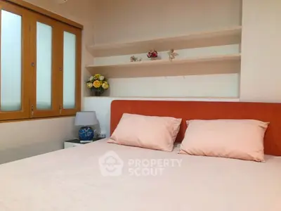 Cozy bedroom with orange headboard and built-in shelves, perfect for relaxation.