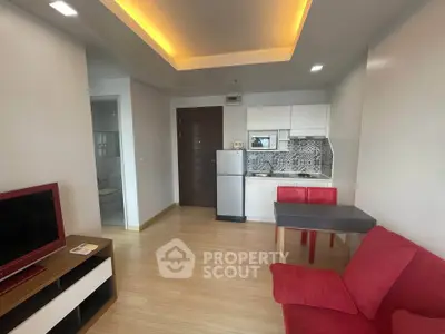 Modern living room with open kitchen, red sofa, and stylish decor in a cozy apartment.