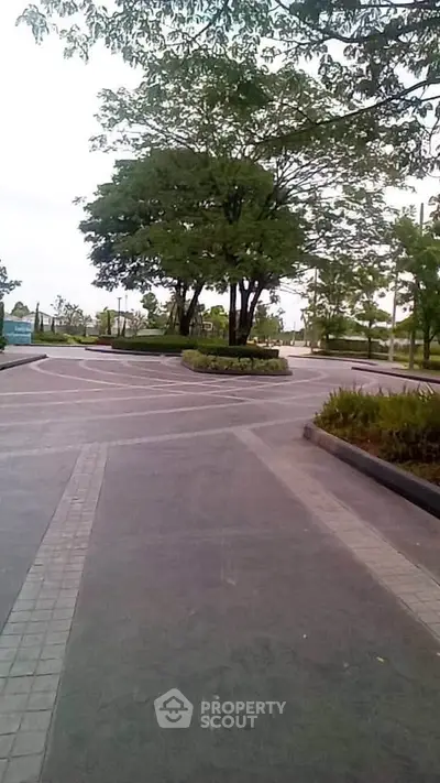 Spacious outdoor area with lush greenery and paved walkways in a serene real estate setting.
