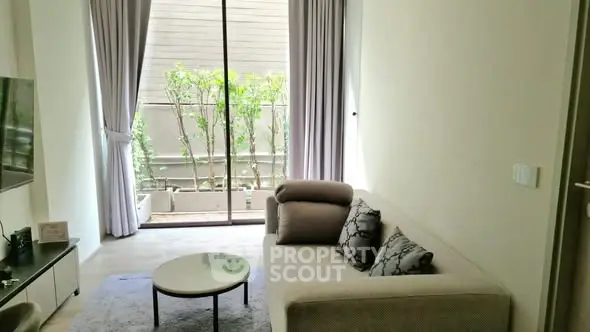 Modern living room with cozy sofa and large window overlooking greenery.